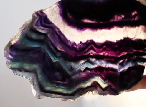 A translucent fluorite slice with purple, pink, and green banding