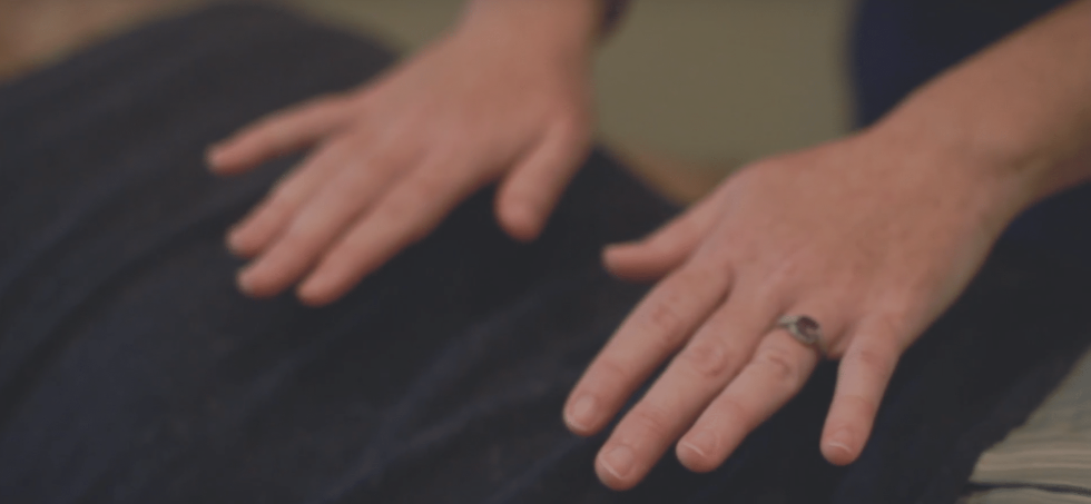 Katie's hands resting gently above a fully clothed client during a Healing Touch session