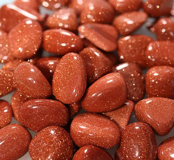 A pile of sparkling tumbled goldstone pocket stones