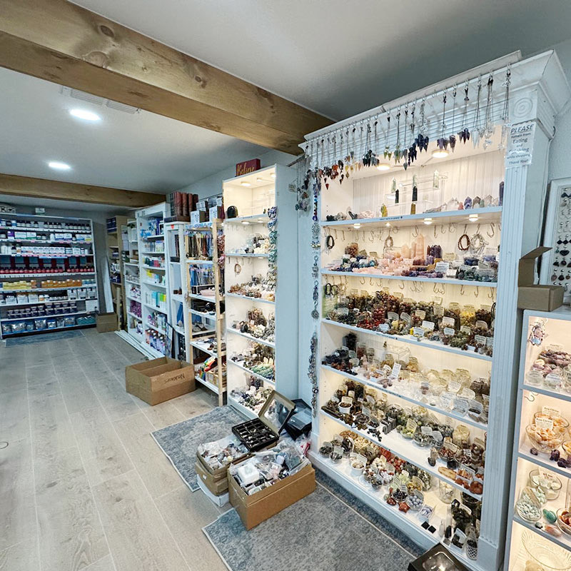 Floor-to-ceiling gemstone shelves holding tumbled stones, jewelry, and specimens