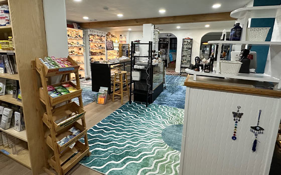Inside the new Divine Wellness shop, with wooden shelving, product displays, the checkout counter, and a teal wave rug