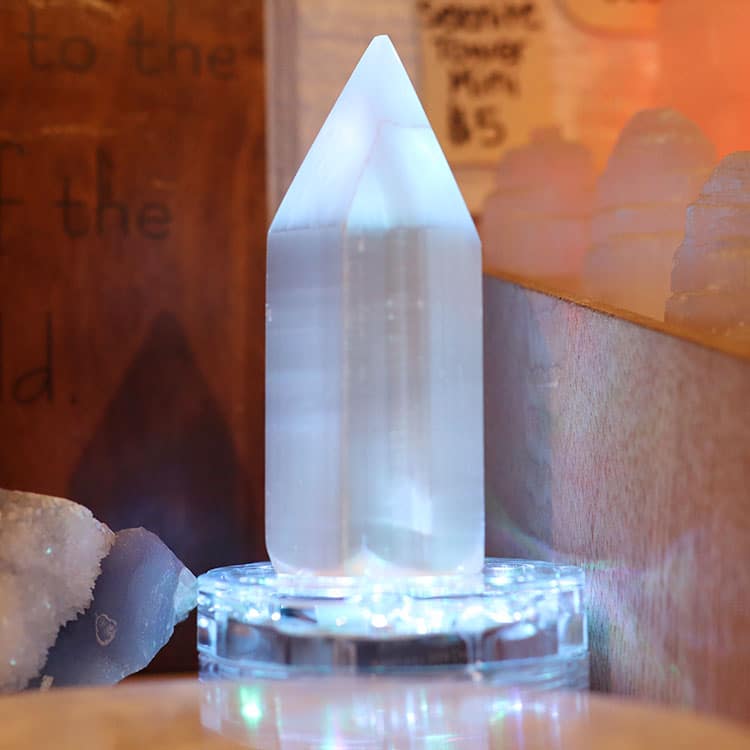 A polished crystal tower lit from below on a display stand in the shop