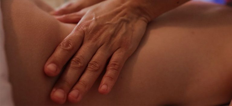 A massage therapist's hand working along a client's back during a session at Divine Wellness, Winter Garden, FL